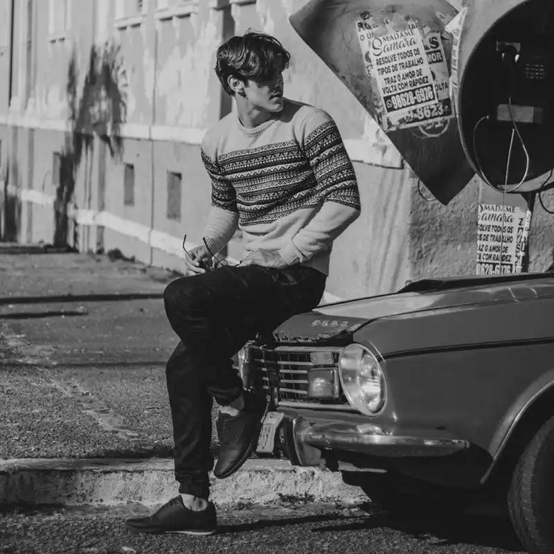 Homme assis sur une voiture.